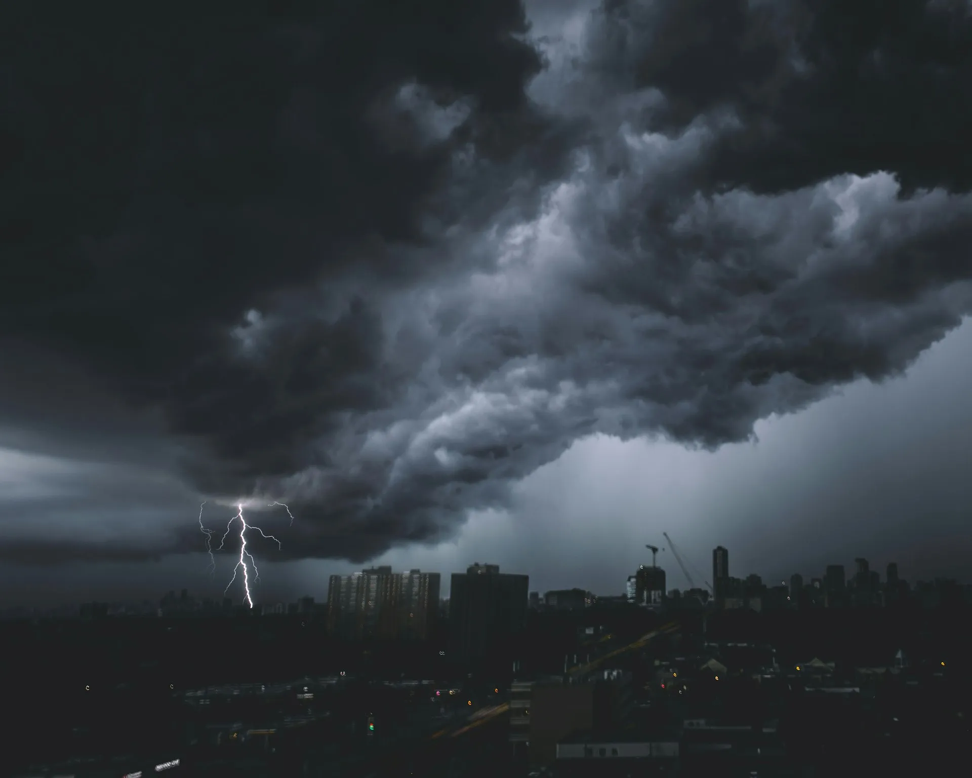 Nubes de tormenta y un rayo sobre una ciudad al anochecer